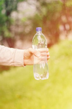 adam hipster doğada su ile plastik bir şişe tutan. sağlıklı yaşam tarzı, yaz, ısı. Parkta yürüyün.