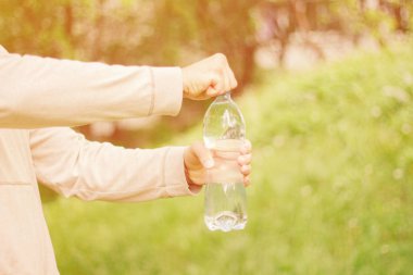 adam hipster doğada su ile plastik bir şişe tutan. sağlıklı yaşam tarzı, yaz, ısı. Parkta yürüyün.