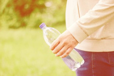 adam hipster doğada su ile plastik bir şişe tutan. sağlıklı yaşam tarzı, yaz, ısı. Parkta yürüyün.