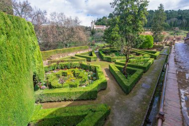 İspanya 'nın Granada kentindeki tarihi Alhambra Sarayı' nda nemli taş yollarla kaplı bulutlu bir günde geniş bahçelerin ve mimari unsurların manzarası..