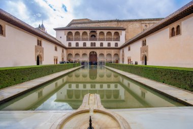 Granada, İspanya - 12 Mart 2025: Alhambra Sarayı 'ndaki güzel Patio de los Arrayanes. Uzamış gölet gökyüzünü ve Nasrid mimarisini yansıtıyor..