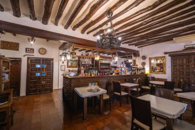 Antequera, İspanya - 12 Mart 2025: Açığa çıkmış tavan kirişleri ve taş barın yer aldığı otantik İspanyol restoranı. Fenerli geleneksel dekor.