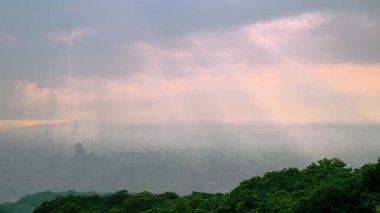 Tayvan 'daki Dadao Dağı' ndan Taipei şehrinin üzerinde nefes kesici bir şafak. Güneş ışınları bulutları delip geçer, turuncu sisle kaplanmış şehir manzarasını aydınlatır..