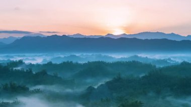 Time lapse of the spectacular autumn sunrise over the misty hills of Er-Liao in Zhuo-Zhen Tainan Taiwan Sun rays pierce the morning fog creating beautiful light.