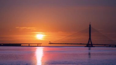 Dramatic sunset sky over the Danjiang Bridge construction site in Tamsui New Taipei Taiwan The cable-stayed bridge and tower form a striking silhouette against the golden light.
