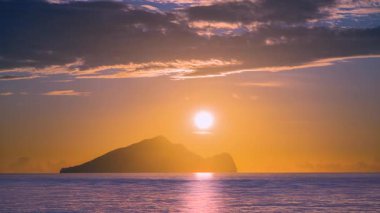 Time lapse of the sun slowly rising from behind Guishan Island in the Pacific Ocean near Zhuangwei Yilan Taiwan The golden light creates a dreamy and spectacular seascape at dawn