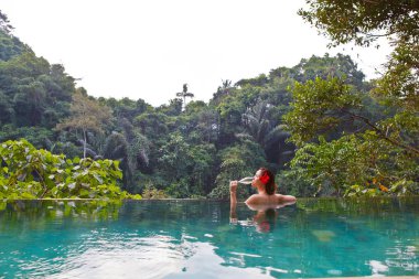 bir kadeh şampanya ile tropik orman havuzdaki kız