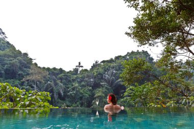 bir kadeh şampanya ile tropik orman havuzdaki kız