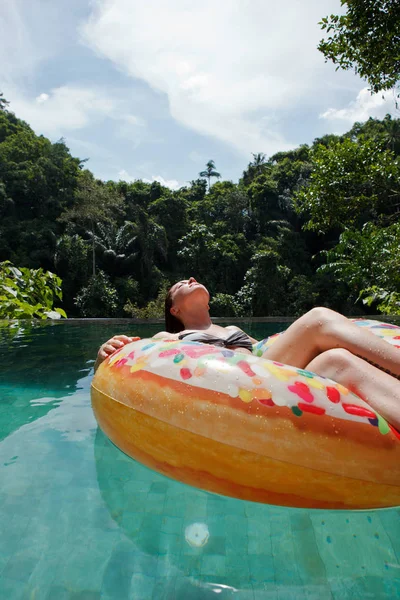 girl in the tropic pool at inflatable ring