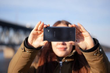 Girl taking photo on brand new Samsung Galaxy S10 clipart