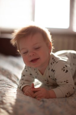 İlk dişleri sırıtan bebek yatakta.