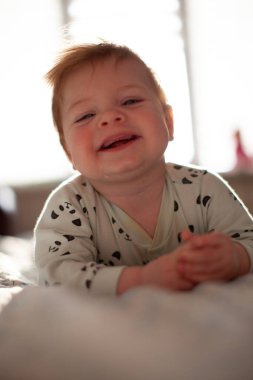 İlk dişleri sırıtan bebek yatakta.