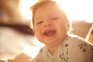 İlk dişleri sırıtan bebek yatakta.