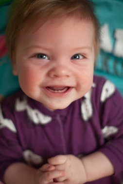 İlk dişleri sırıtan bebek yatakta.