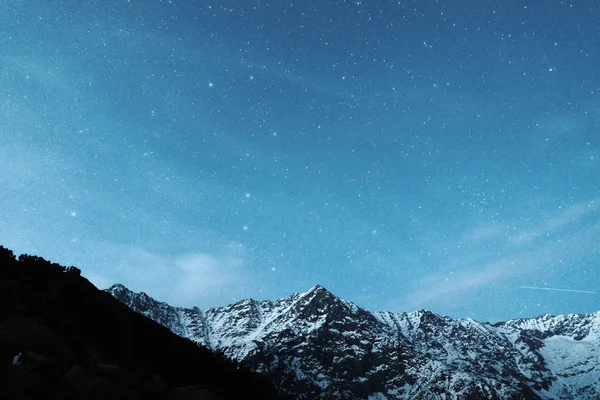 Cielo estrellado sobre un fondo de montañas nevadas — Foto de Stock