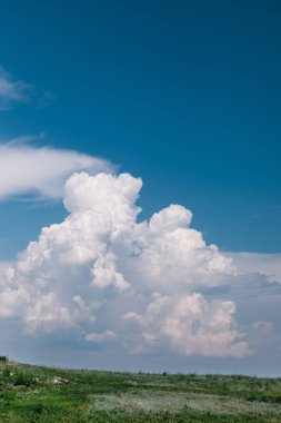 Mavi gökyüzü bulutlu yeşil bir yüzey üzerinde