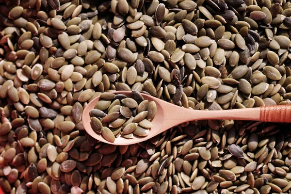 Un cucchiaio di legno giace su molti semi verdi di zucca ed è pieno di loro. — Foto Stock