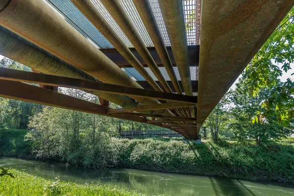 A view from beneath a rusty metal walking bridge that spans the Green River in Kent, Washington.