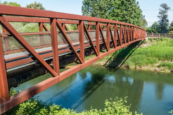A rusty metal walking bridge spans the Green River in Kent, Washington.