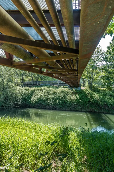 A view from beneath a rusty metal walking bridge that spans the Green River in Kent, Washington.