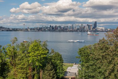 Bir mavna Seattle manzarası önünde bir römorkör çeker.