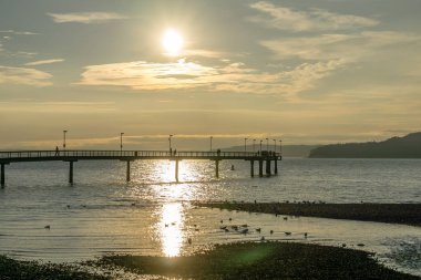 Güneş Des Moines, Washington'da iskele üzerinde asılı.
