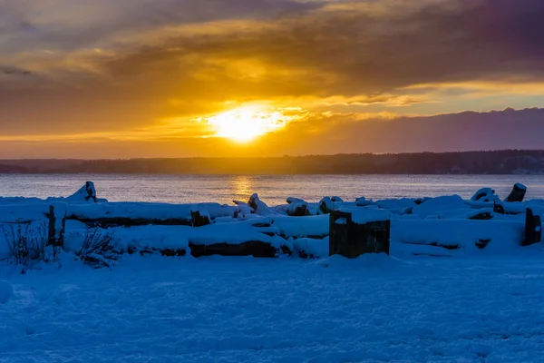 Snow covers the ground as the sun set over the Puget Sound.