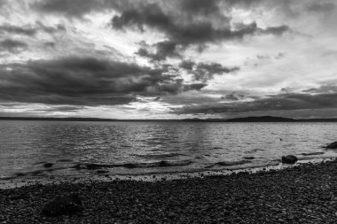 Gün batımında Puget Sound 'un üzerinde kara bulutlar asılı. Fotoğraf Batı Seattle, Washington 'da çekildi..
