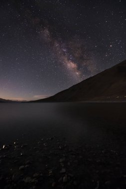 Nehir ve dağ arka planda Samanyolu ile yıldızlı gece.