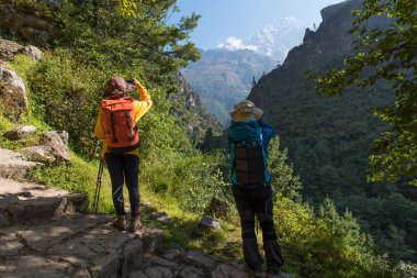 Sırt çantası ve trekking kutup ile güzel dağ önünde duran iki genç trekking kadınların güzel bir sahne.