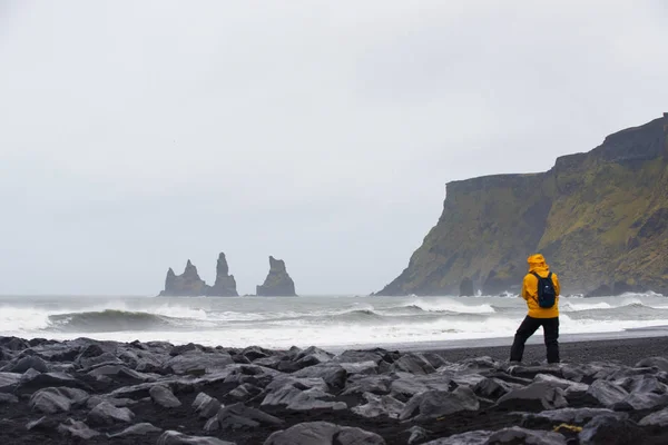 Alone man get wet on a black sand beach volcanic rocks in Vik, Iceland