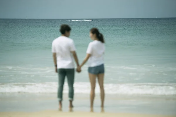 Blur of back view asian couple holding hand standing in sea on honeymoon period,mood and tone with valentine concept.