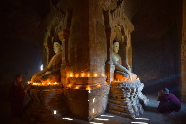 İki acemi mum yakıp bagan pagoda Myanmar içinde dua.