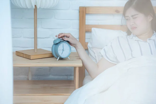 Wake up of an asleep Asian Girls stopping alarm clock on bed