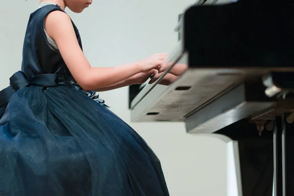 Рука девушки в красивом платье играет на пианино, выступление в музыкальной школе — стоковое фото
