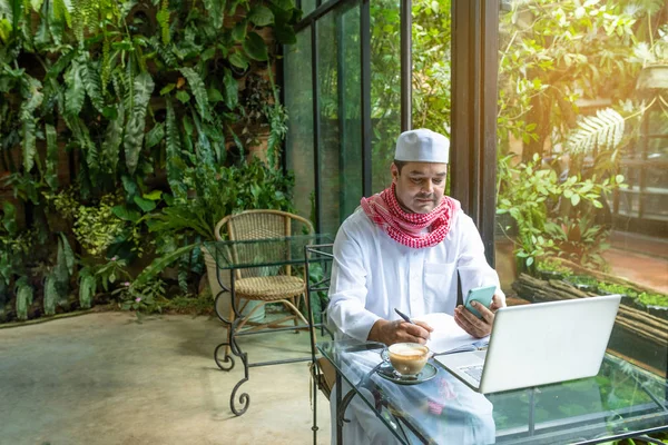 Pakistani muslim arab man hand hold smart mobile phone and lapto