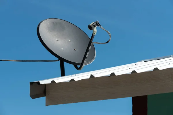 Negro antena parabólica en la casa del techo con cielo azul . — Foto de Stock