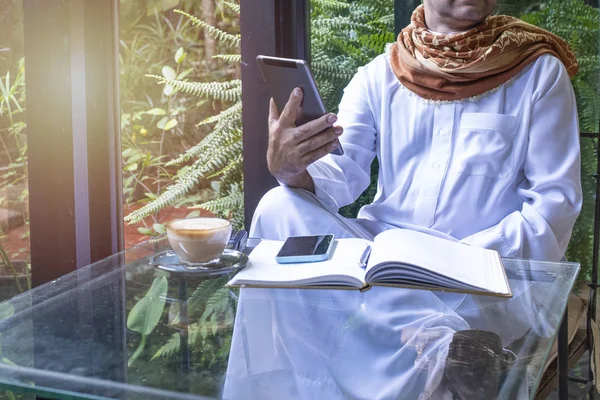 Paquistanês muçulmano Homem trabalhando no computador tablet no café, mão segurar tablet e escrever livro com coffee.business conceito freelance . — Fotografia de Stock