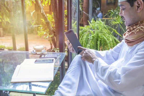 Pakistaní musulmán Hombre que trabaja en la computadora de la tableta en la cafetería, la tableta de mano y escribir libro con coffee.business concepto freelance . — Foto de Stock