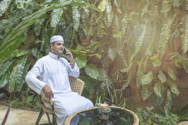 Paquistanês de negócios asiático homem usando telefone celular inteligente, falar com rosto sério desgaste vestido muçulmano sentar no café, conceito de negócio freelance . — Fotografia de Stock