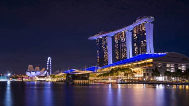 Alacakaranlık zamanında waterbay üzerinde refleksi ile şafakta Singapur iş bina silueti. Geceleri Işıklı Marina defne kumu