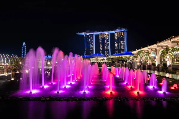 Bahía marina de Singapur iluminada arena con espectáculo de fuentes en la noche alrededor de la zona de negocios de construcción en Singapur . —  Fotos de Stock