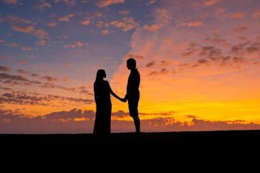Çiftin siluetleri gün batımı gökyüzüne karşı romantik erkek ve kadın, el ele tutuşur. Sevgililer tema ve vintage fotoğraf.