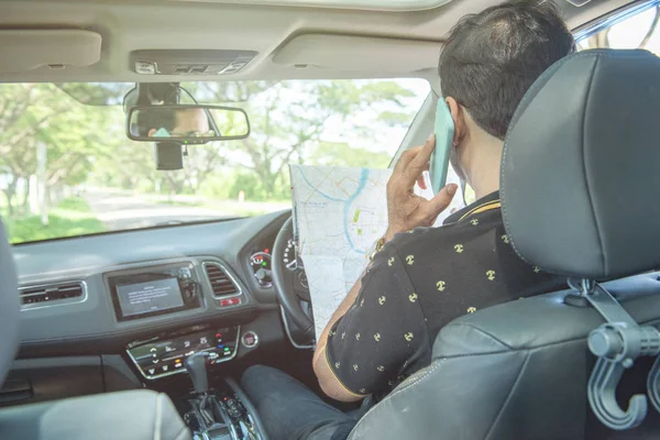 Asiático guapo hombre uso de teléfono en coche con buscando en mapa . — Foto de Stock