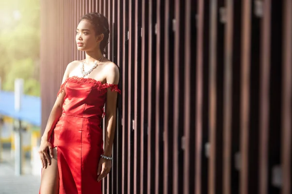 Красивый портрет азиатская женщина платье в красной моде вечернее платье действовать как модель и опираться на деревянную стену — стоковое фото