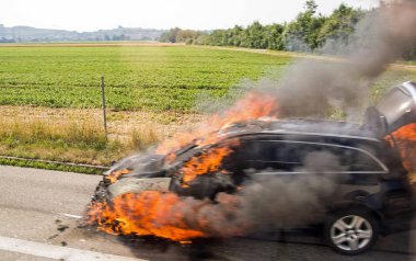 Hiç yaralanmadan yol kenarında yanan bir araba.