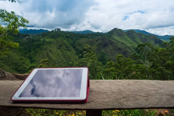 Tablet digital na mesa de madeira com vista para a montanha . — Fotografia de Stock