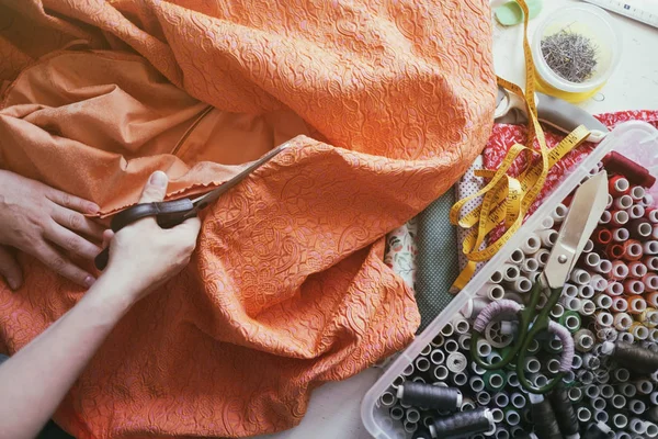 Біла дівчина ріже помаранчеву тканину — стокове фото