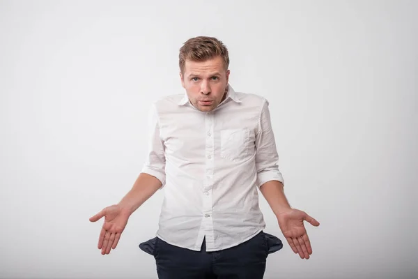 Stressato giovane caucasico mostrando tasche vuote. Concetto di niente denaro . — Foto Stock