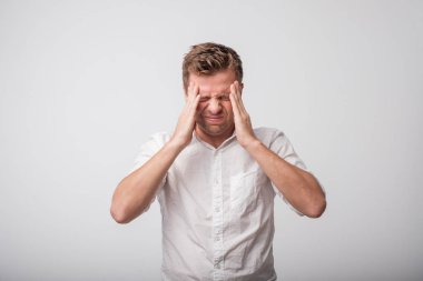 Beyaz genç adam kafasını dokunmaktan ve having baş ağrısı beyaz gömlekli